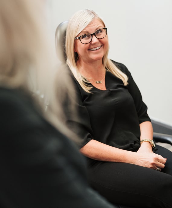 A photo of a smiling woman while sitting in the dental chair 