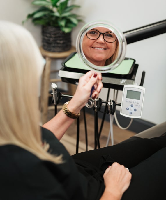 A photo of our patient looking in the mirror with happy smile 