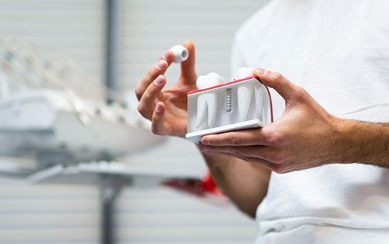Dentist placing a dental crown on a model of a dental implant