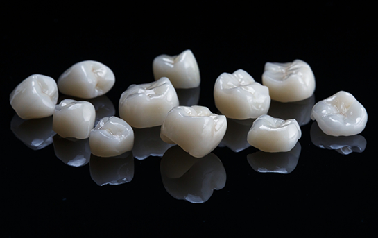 Multiple tooth colored dental crowns against a black background