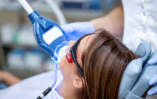 Dental patient having her teeth whitened with a special light