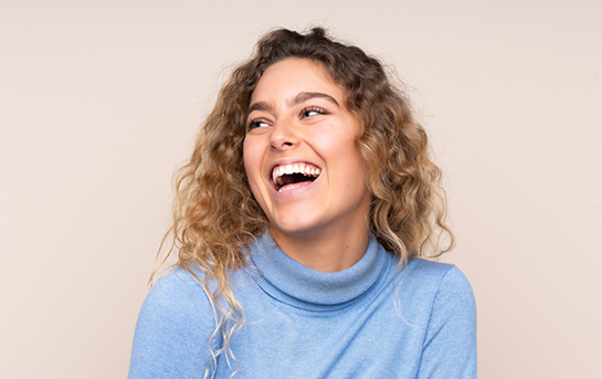 Woman with curly dark blonde hair laughing
