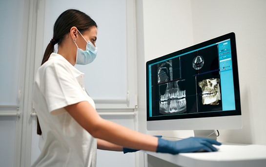 Dentist looking at x rays of a patients teeth on a computer