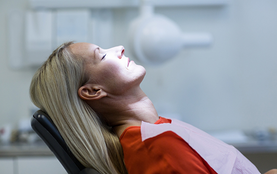 Woman leaning back in the dental chair with her eyes closed