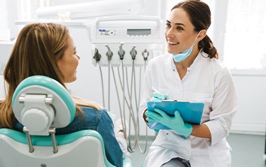 Dentist smiling while taking notes on clipboard