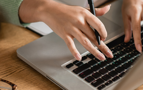 Hands typing on a laptop
