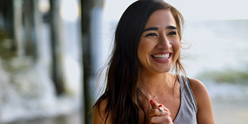 Young woman with long dark hair smiling in the sun