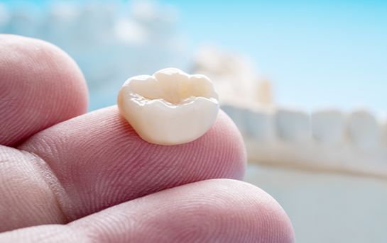Close up of a dental crown resting on a finger